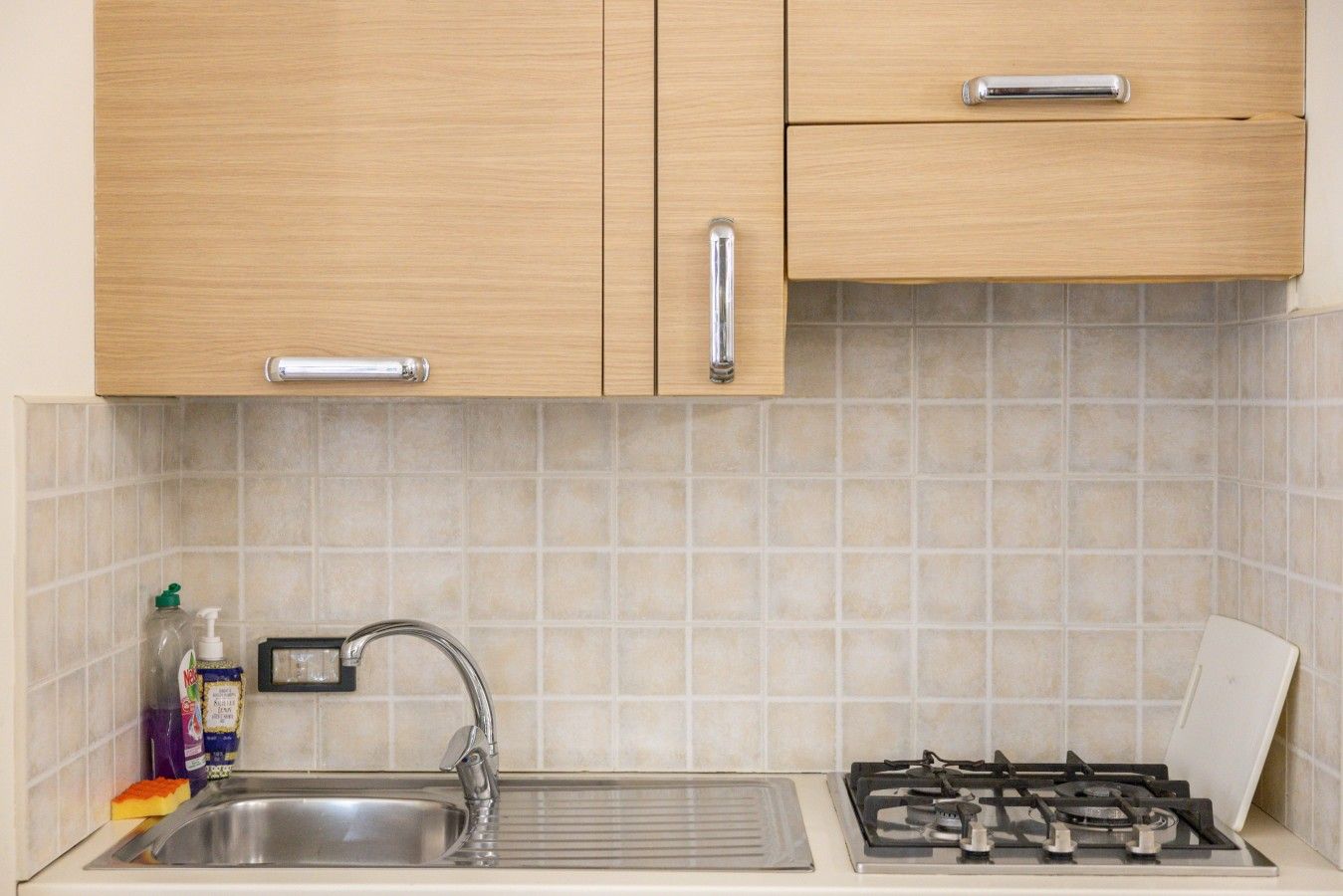 A kitchen with wooden cabinets, a stainless steel sink, and a gas stove.
