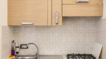 A kitchen with wooden cabinets, a stainless steel sink, and a gas stove.
