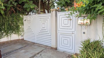 A gated entrance with a white fence, a mailbox, and a potted plant.