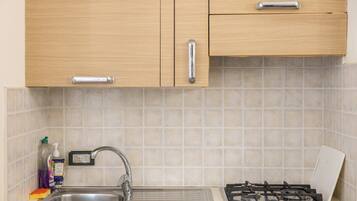 Una cocina con un lavamanos de acero inoxidable, una estufa a gas y armarios de madera.