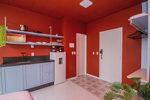 Una cocina compacta con armarios blancos, un refrigerador y una encimera con varios objetos.