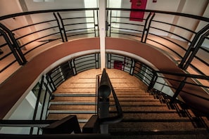 Una escalera curva con barandillas de metal y peldaños alfombrados.