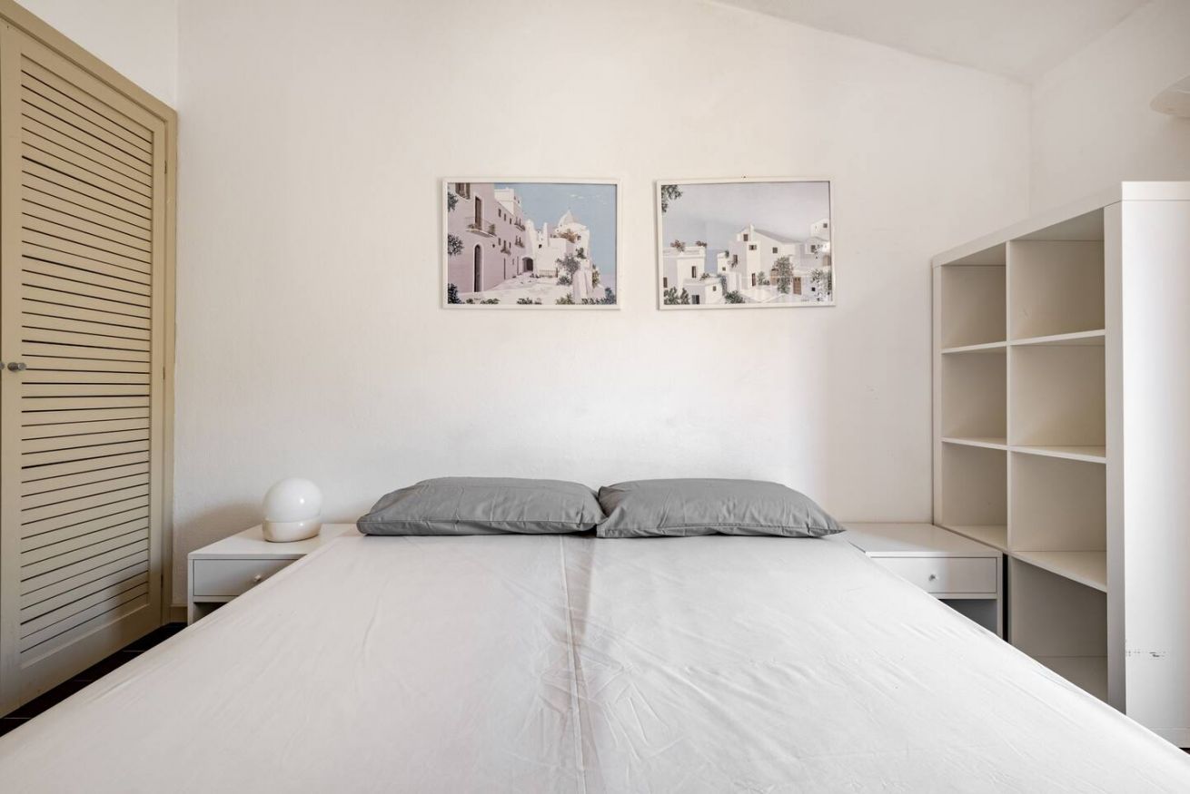Ein Schlafzimmer mit einem Bett, zwei Nachttischen, einer Nachttischlampe, einem Kleiderschrank und zwei gerahmten Bildern an der Wand.