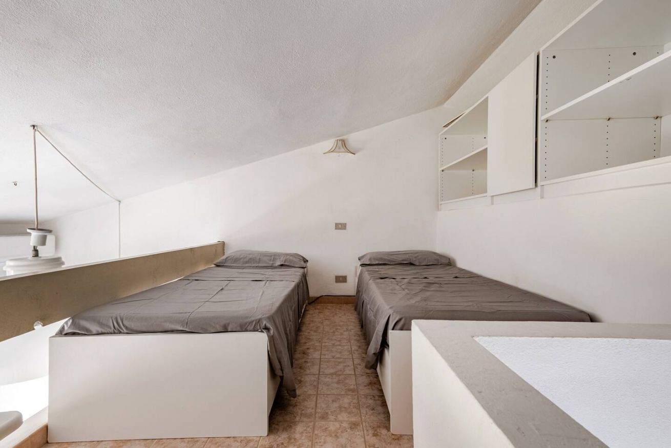 Une chambre de dortoir avec deux lits simples, un bureau, une chaise, une lampe et un miroir au mur.