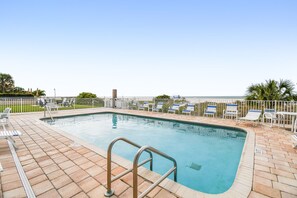A swimming pool with a metal ladder, lounge chairs, and a view of the ocean. - Beachfront Retreat with Private Elevator (Indian Rocks Beach)
