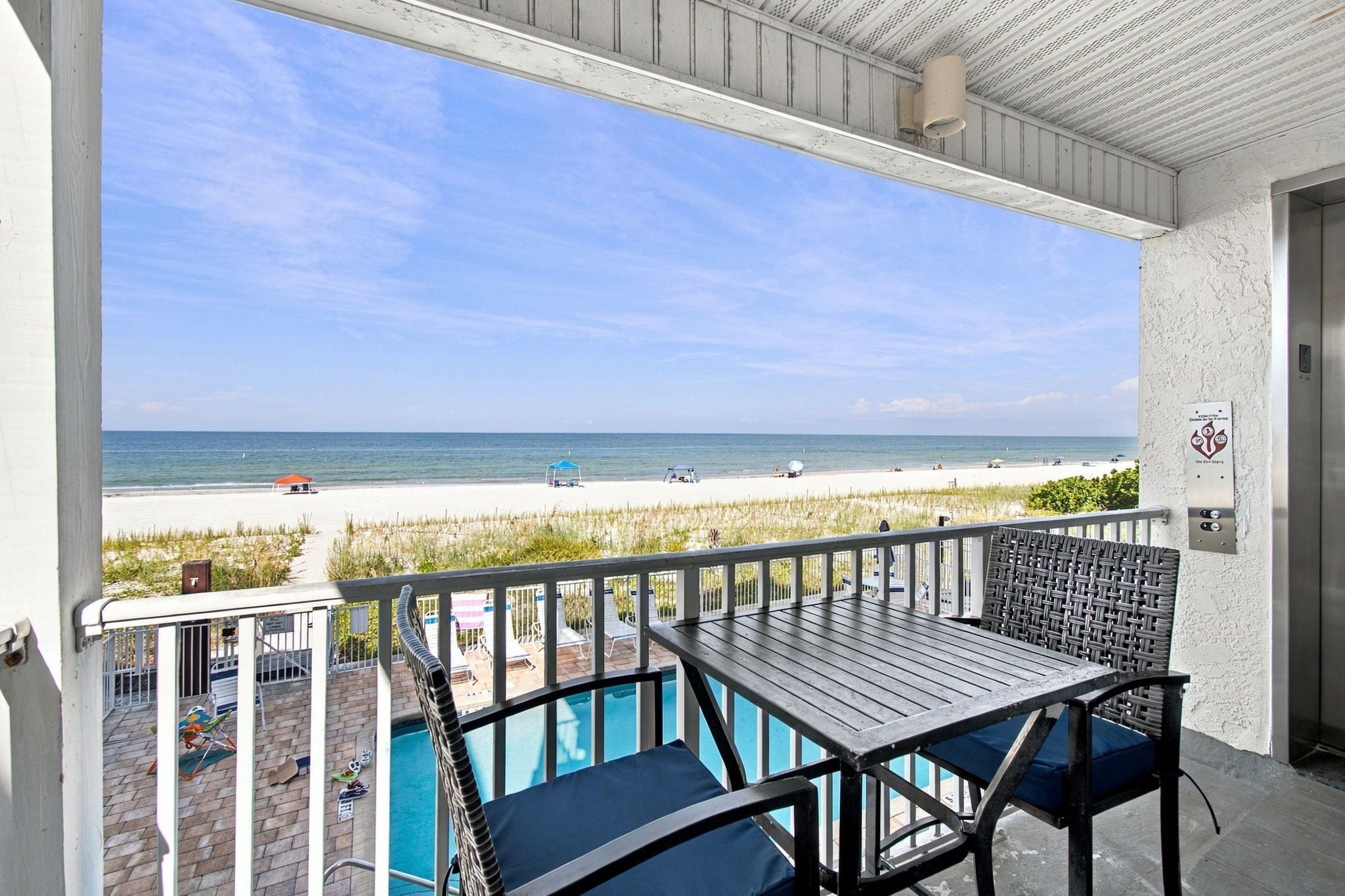 Un balcon avec vue sur une plage et une piscine.