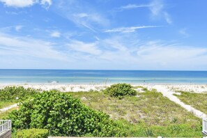 A beach view with a clear sky, sandy beach, and green vegetation. - Beachfront Retreat with Private Elevator (Indian Rocks Beach)