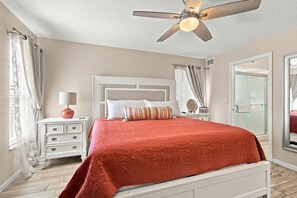 A bedroom with a bed, nightstands, a ceiling fan, and a glass shower door. - Beachfront Retreat with Private Elevator (Indian Rocks Beach)