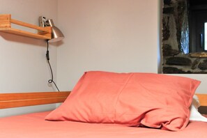 A bed with a wooden headboard, a pink pillow, and a wall-mounted lamp. - Holiday Home 'Casa Yañez Duplex' with Mountain View, Shared Garden and Wi-Fi (Chantada)