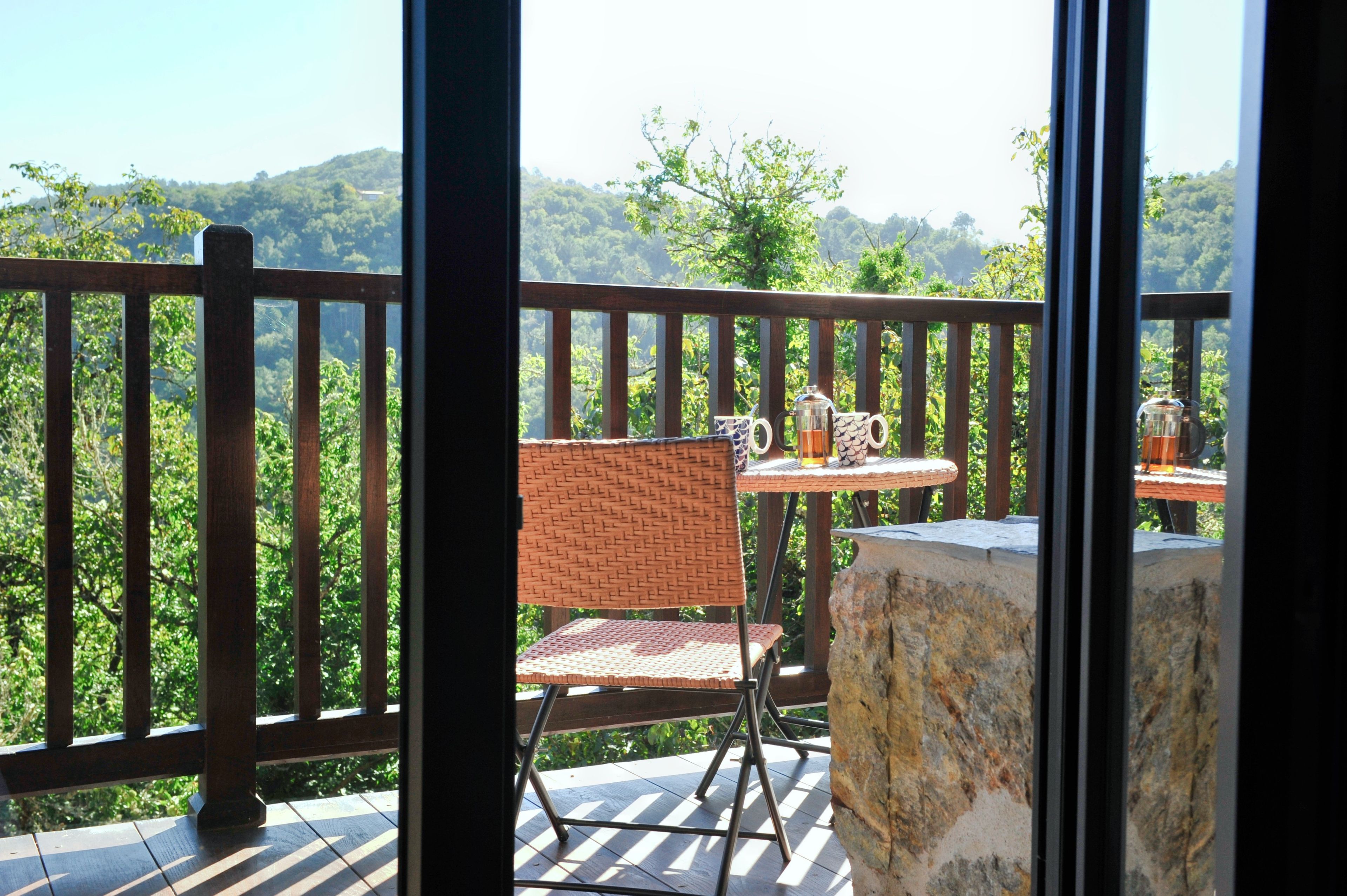 A balcony with a wicker chair, a small table, and a stone pillar.