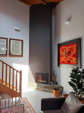 A living room with a fireplace, a staircase, and a large framed artwork on the wall. - Casa de vacaciones 'Casa Yañez' con vistas a la montaña, terraza y Wi-Fi (Chantada)