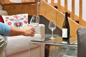 A person holding a wine glass, a bottle of wine, and a glass on a glass table in a room with a staircase. - Casa de vacaciones 'Casa Yañez' con vistas a la montaña, terraza y Wi-Fi (Chantada)