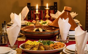 Una mesa de comedor dispuesta con diferentes platos, un tagine marroquí tradicional y una botella de aceite de oliva.