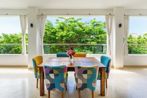 A dining area with a table and chairs, large windows with curtains, and a view of greenery outside. - 2bedroom apartment in Diani Beach with AC, Internet, private access to the beach (Diani Beach)