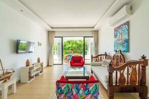 A living room with a sofa, a red armchair, a television, and a painting. - 2bedroom apartment in Diani Beach with AC, Internet, private access to the beach (Diani Beach)
