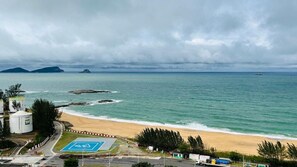 Vista costera con playa, zona de estacionamiento y estructuras industriales.