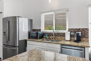 A modern kitchen with a stainless steel refrigerator, a built-in toaster, a sink, and a coffee maker. - 3 Bedroom/ Private Fenced Backyard /Desert Style (Gilbert)