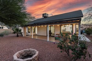 A modern house with a covered patio, a stone fire pit, and a view of the sky. - 3 Bedroom/ Private Fenced Backyard /Desert Style (Gilbert)