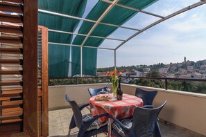 Ein Balkon mit Tisch, Stühlen und Blick auf eine Stadt.