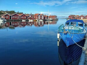 Ein ruhiger Hafen mit roten Gebäuden und einem blauen Boot, das vor Anker liegt.