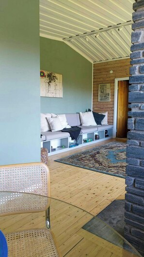Un espacio de sala acogedor con un sofá, cojines, un tapete estampado y una pared de piedra.