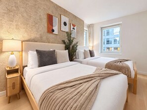 Une chambre d’hôtel avec deux lits, une table de chevet avec une lampe et des œuvres d’art accrochées au mur.