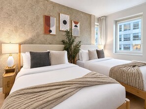 Habitación de hotel con dos camas, un ventanal grande y un cuadro abstracto en la pared.