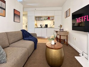 Un salón moderno con sofá, mesa de centro y televisor mostrando el logotipo de Netflix.