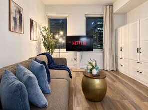 A modern living room with a sofa, a coffee table, and a TV displaying the Netflix logo.