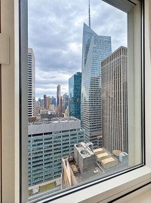 Un immeuble de grande hauteur doté d’une façade en verre incurvée remarquable, entouré d’autres gratte-ciel et surplombé par un ciel nuageux.