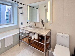 Une salle de bain moderne dotée d’une grande fenêtre, d’un lavabo avec un miroir, de toilettes et d’un espace douche.