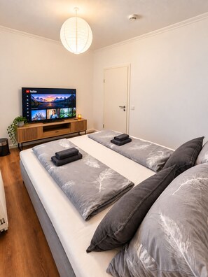 A modern bedroom with a bed, a TV, and a door.
