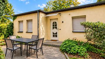 Eine Terrasse mit Tisch und Stühlen, einer Tür und einem kleinen Garten.