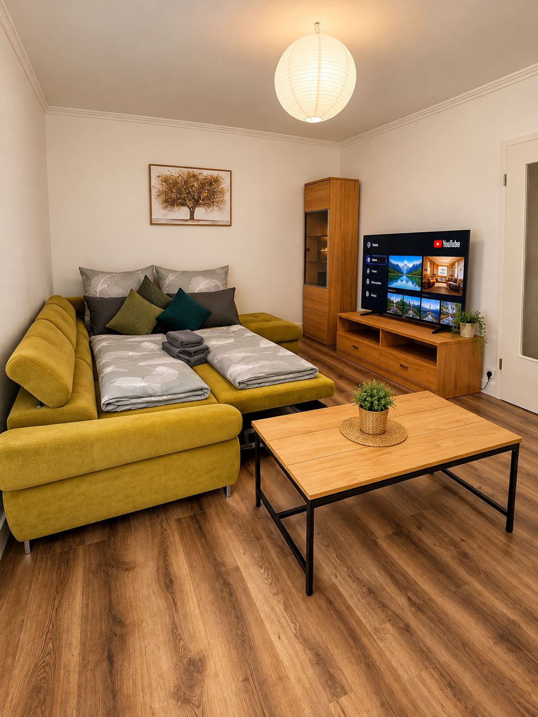 A modern living room with a sofa, a coffee table, a TV, and a wooden cabinet.