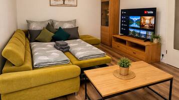 A modern living room with a sofa, a coffee table, a TV, and a wooden cabinet.