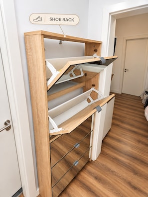 Una scarpaio con diversi scomparti, un armadietto in legno e una porta sullo sfondo.
