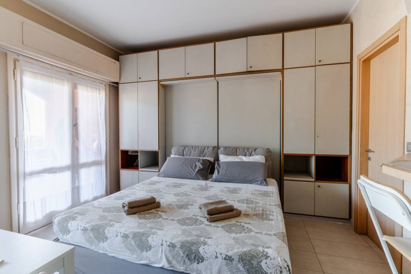 A bedroom with a bed, a wardrobe, and a window.