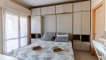 A bedroom with a bed, a wardrobe, and a window.