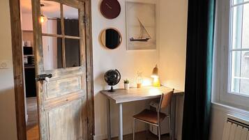 Een kamer met een houten deur, een bureau met stoel, een wereldbol, een lamp en een raam met gordijnen.