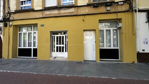 Un bâtiment jaune avec une entrée au rez-de-chaussée, une porte et des fenêtres.