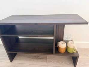 Um console de madeira escura com três prateleiras e uma prateleira inferior, acompanhado por duas canecas do lado direito.