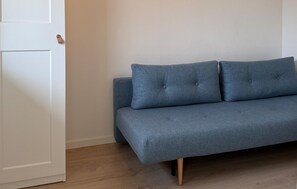 A room with a grey sofa against a white wall and wooden flooring. - 2 bedroom beautiful home in Slagelse (Slagelse)