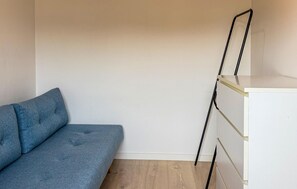A room with a blue sofa, a white cabinet, and a wooden floor. - 2 bedroom beautiful home in Slagelse (Slagelse)