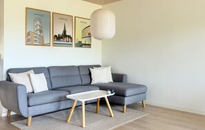 A grey sectional sofa with wooden legs, a white coffee table, and a hanging paper lantern. - 2 bedroom beautiful home in Slagelse (Slagelse)