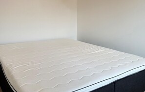 A bed with a white mattress and a black headboard. - 2 bedroom beautiful home in Slagelse (Slagelse)