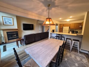 A modern kitchen with wooden cabinets, a dining area with a large table and chairs, a built-in TV, and a fireplace. - Multi-level, spacious, AC/FP, Mtn Views, Deck, Swim Club. F0372 by LRS (Lincoln)