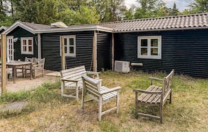 A rustic cabin with a wooden table and two chairs in the foreground, and a window with a view of the surrounding trees. - 2 bedroom lovely home in Nykøbing Sj (Nykøbing Sj)