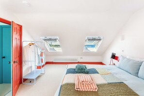 A bedroom with a bed, a radiator, a window, and a door. - Panoramic harbour views & fireplace | Porthva (Cornwall)