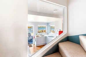 A modern interior with a kitchen, dining area, and a view of a marina. - Panoramic harbour views & fireplace | Porthva (Cornwall)