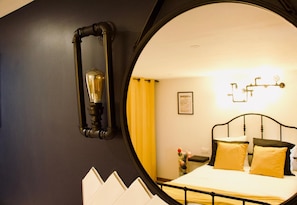 A bedroom with a bed, a mirror, and a wall-mounted light fixture. - Villa Trouz Ar Mor (Audierne)